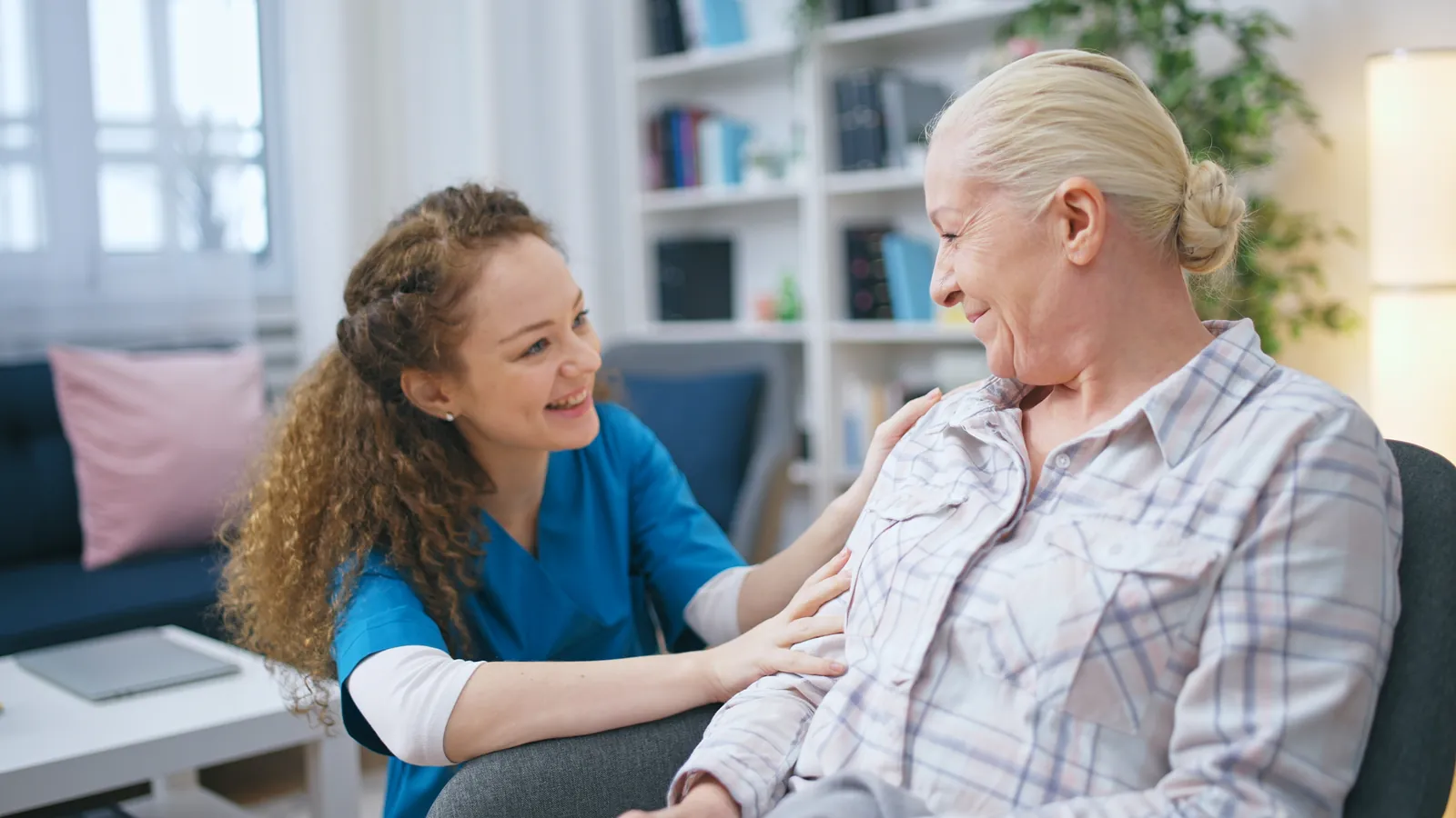 Care worker comforting a seated older woman